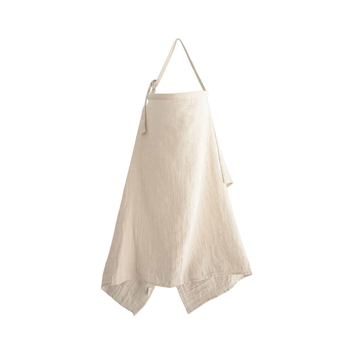 The mushie Muslin Nursing Cover, in a cream-colored textured linen, hangs by its neck strap against a white background. This simple, draped design with an unfinished hem offers adjustable coverage and blends style with everyday practicality.